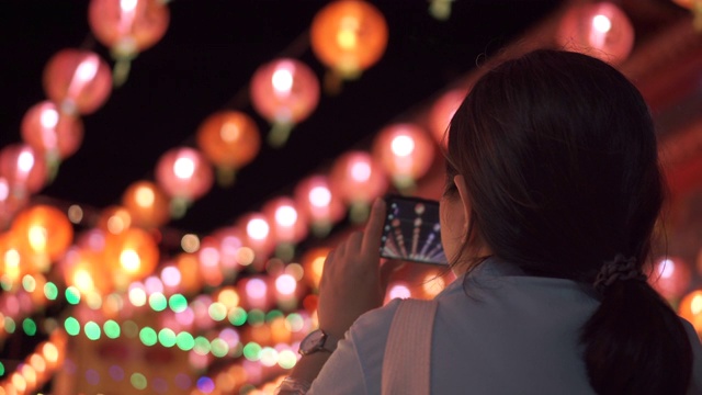 亚洲女人用智能手机拍挂在上面的漂亮灯笼。