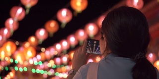 亚洲女人用智能手机拍挂在上面的漂亮灯笼。