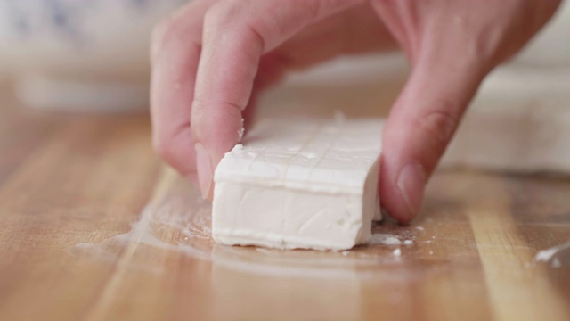 用手将羊乳酪切成小方块，放在砧板上