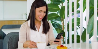 在咖啡馆或咖啡店使用智能手机的亚洲女性