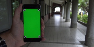 4K白人男子显示绿色屏幕手机在过道与柱