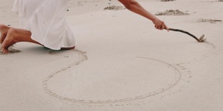 年轻女子在沙滩上画心形