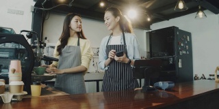 年轻美丽的亚洲女咖啡师穿着围裙在咖啡厅的柜台接受顾客的电话订购咖啡面带微笑。咖啡店和小型咖啡店的概念。