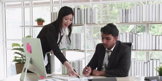 两个商业人士男人和亚洲女人在黑色西装谈论规划商业战略。他们指出文书工作市场计划研究。商业团队合作，头脑风暴的概念