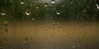雨点落在有云背景的窗玻璃上。雨滴的自然模式。在雨中开车。从车窗往下看
