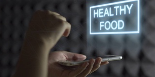 人类的手握智能手机屏幕显示全息图，并滑动改变菜单垃圾食品为健康食品。食物改变全息图
