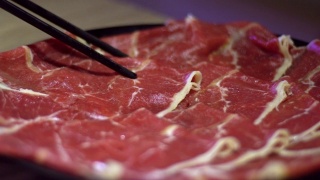 用筷子夹住牛肉生肉的慢动作。北京的中国火锅视频素材模板下载