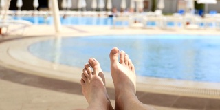 男人的脚在游泳池的背景下，放松度假