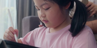 亚洲的祖父母和孙女在家用平板电脑画画。高三的中国，爷爷奶奶和小女孩躺在客厅的沙发上，开心地度过家庭时光，放松心情。缓慢的运动。