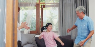 亚洲的祖父母和孙女在家一起听音乐和跳舞。中国老年人，爷爷和奶奶愉快地度过家庭时间和年轻女孩在客厅放松的概念。缓慢的运动。
