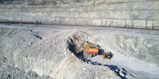 鸟瞰图挖掘机在石棉坑中挖掘灰色土丘