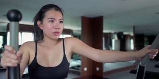 健身房锻炼的年轻美丽和流汗的亚洲韩国女人训练在酒店或健身俱乐部努力在有氧椭圆机运动和健康的生活方式的概念