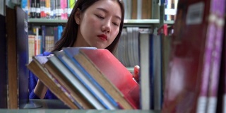 一个亚洲女人在图书馆找书的4k视频场景