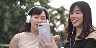 两个亚洲女性朋友听音乐和跳舞户外