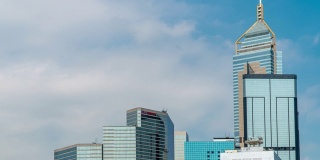 4K时间推移低角度视野广角摩天大楼玻璃大楼塔在商业和金融领域与移动的白云和清澈的蓝天。中国香港的商业金融中心