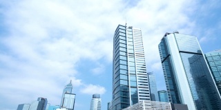 4K时间推移低角度视野广角摩天大楼玻璃大楼塔在商业和金融领域与移动的白云和清澈的蓝天。中国香港的商业金融中心