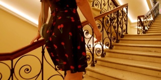 一个年轻漂亮的时尚女孩的腿踩着高跟鞋走在古老的经典楼梯在商店画廊。慢动作