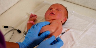 戴手套的护士在医院为早产儿接种疫苗。新生儿中心重症监护病房。特写镜头。医生准备用注射器将疫苗注射到婴儿手臂的手。4 k