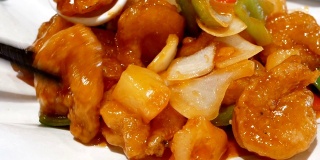 在中餐馆里，人们在餐桌上吃炸虾和蔬菜的动作