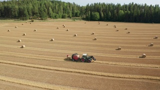 鸟瞰图的拖拉机收集干草和释放干草辊在田间视频素材模板下载