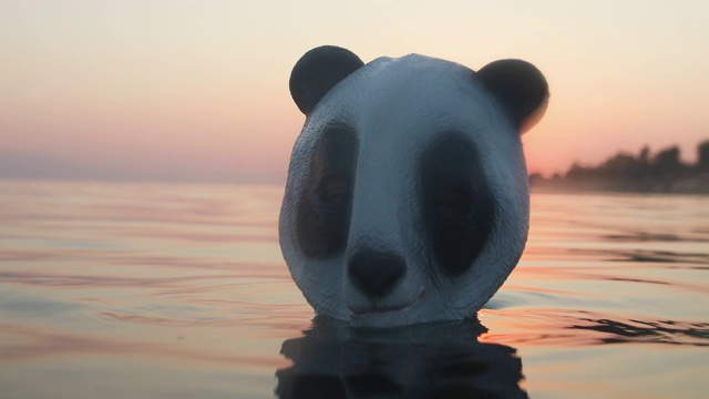 暑假里，海里的男人戴着熊猫头面具