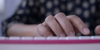 一个女人的双手在桌子上敲击键盘。
