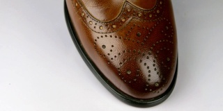 特写，旋转一个时尚的经典棕色鞋带鞋。
