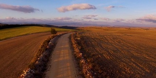 鸟瞰镜头飞行在美丽的乡村道路在日落的乡村景观。