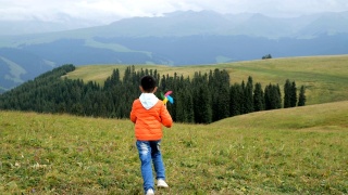 一个亚洲男孩在草原上玩风车视频素材模板下载