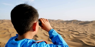 一个小男孩在沙漠里用望远镜看
