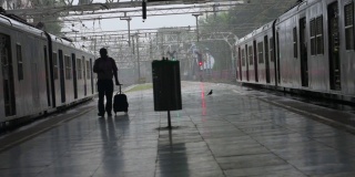 一位老人提着旅行袋走在火车站的月台上