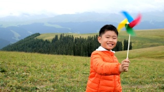 一个亚洲男孩在草原上玩风车视频素材模板下载