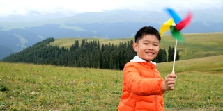 一个亚洲男孩在草原上玩风车