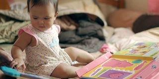 亚洲女婴玩和阅读剧本或活动书与母亲