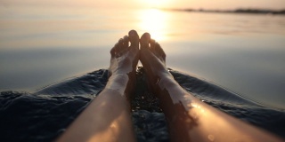 赤脚女人在暑假的海上放松。坐在船上的女人的脚在水里