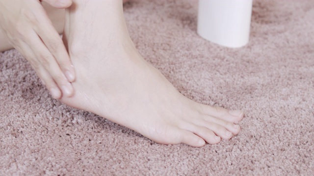 亚洲成年妇女用手在她的脚上涂抹保湿霜。身体保健的概念。