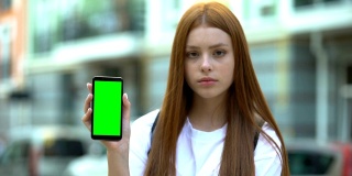 红发女孩展示绿色屏幕的智能手机，免费导航应用