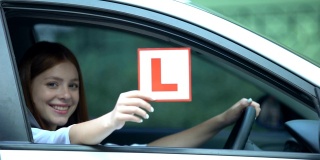 微笑的女孩在车窗上显示l号车牌，驾驶路线，左车流
