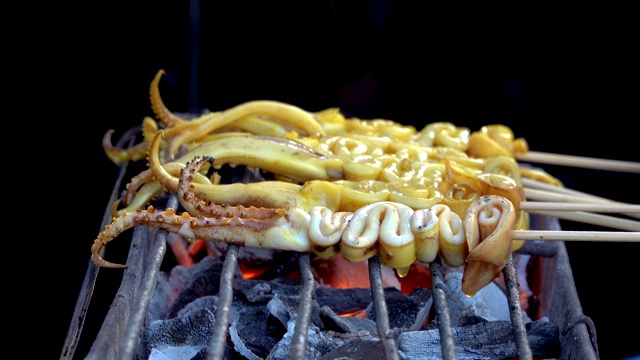 在食品市场的烤架上烤鱿鱼是泰国的街头小吃