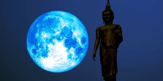 超级蓝满月移动在夜空和剪影佛