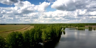 美丽的蓝色河流在森林的岸边，靠近无尽的田野
