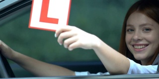 微笑的少女显示L车牌坐汽车，驾驶证考试