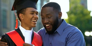 极为快乐的黑人父亲恭贺儿子身着西服，毕业了