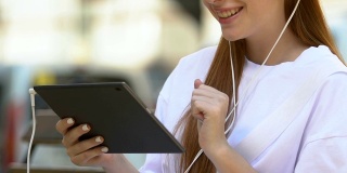 带着耳机微笑的大学生使用平板电脑，网上购物app，小玩意