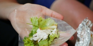 游客准备和吃春卷的米纸包装或banh trang在晚上的街头小吃市场。传统越南nem菜，亚洲美食。近距离
