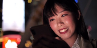 迷人的亚洲女人在街上走路时使用手机