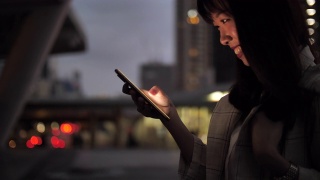 迷人的亚洲女人在街上走路时使用手机视频素材模板下载