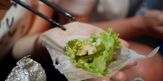 游客准备和吃春卷的米纸包装或banh trang在晚上的街头小吃市场。传统越南nem菜，亚洲美食。近距离