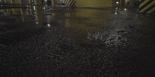 超市停车场内景拍摄，水滴滴落在停车场的地面上，形成水坑。