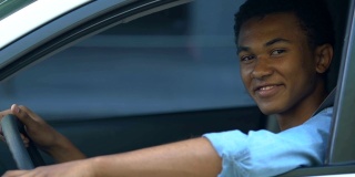 非裔美国少年在车里竖起大拇指，拿驾照